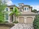 Two-story house with beige walls, tile roof, and two-car garage at 395 Muirfield Loop, Reunion, FL 34747