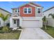 Two-story house with gray and burnt orange siding, two-car garage, and landscaping at 5381 Maddie Dr, Haines City, FL 33844