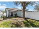 Relaxing backyard featuring a mature tree, white fence, and covered patio with charming French doors at 14457 Jamaica Dogwood Dr, Orlando, FL 32828