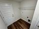 A spacious laundry room featuring a white door, wooden floors, and a metal wire shelf for storage at 238 Locust Rd, Ocala, FL 34472