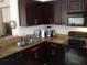 L-shaped kitchen with dark wood cabinets, granite counters and black appliances at 2558 Robert Trent Jones Dr # 1427, Orlando, FL 32835