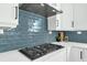Close up of a modern gas range and vent hood with stylish blue tile backsplash at 500 W Hazel St, Orlando, FL 32804
