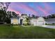 Two-story house with a three-car garage, manicured lawn, and a beautiful sunset at 606 Urick St, Fruitland Park, FL 34731