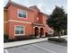 Two-story building with orange exterior, two entrances, and landscaping at 8956 California Palm Rd, Kissimmee, FL 34747