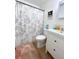 Clean bathroom features a shower with floral curtain, white vanity, and wood-look flooring at 1606 Lime St, Kissimmee, FL 34746