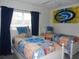 Bright bedroom featuring twin beds with colorful quilts, a window, and themed wall decor at 2803 Lido Key Ct, Kissimmee, FL 34747