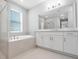 Bathroom featuring a soaking tub, double vanity, large mirrors, and modern fixtures at 2975 Arranmore Dr, Ormond Beach, FL 32174