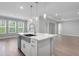 Bright kitchen with a marble island, stainless steel sink, pendant lights, and a view of the outdoor greenery at 2975 Arranmore Dr, Ormond Beach, FL 32174