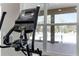 Modern treadmill featuring an LCD screen, with a view of the pool and lounge chairs through bright community center windows at 3238 Arch Ave, Ormond Beach, FL 32174