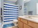 Bathroom with blue and white striped shower curtain and light wood vanity at 351 Michigan Estates Cir, St Cloud, FL 34769