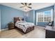 Blue bedroom with wood-look floors, ceiling fan, and large window at 351 Michigan Estates Cir, St Cloud, FL 34769