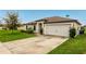 Tan one-story house with a two-car garage and well-manicured lawn at 1952 Piedmont Ct, Mascotte, FL 34753