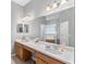 Bathroom with double sink vanity, large mirror, and a view of the tub through an open doorway at 3689 Rolling Hills Ln, Apopka, FL 32712