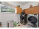 Functional laundry room featuring modern washer and dryer, storage cabinets, and window view at 3689 Rolling Hills Ln, Apopka, FL 32712