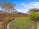 Landscaped backyard with grassy area, wood fence, and stone accents at 385 Alcove Dr, Groveland, FL 34736