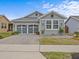 Gray craftsman style home with a three-car garage and landscaped front yard at 385 Alcove Dr, Groveland, FL 34736