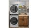 Bright laundry room with stacked washer and dryer, wooden cabinets at 385 Alcove Dr, Groveland, FL 34736
