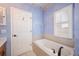 Relaxing bathroom with a soaking tub, a window with stained glass, and neutral tile at 8773 Silk Bay Pl, Orlando, FL 32827