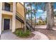 Exterior of a yellow apartment building with black stairs, a sidewalk and tropical landscaping at 1057 S Hiawassee Rd # 1911, Orlando, FL 32835