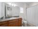 Bright bathroom features a granite countertop, wood cabinets, and shower with curtain at 10824 Royal Cypress Way, Orlando, FL 32836