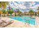 A gorgeous community pool offers plenty of lounge space and palm trees for shade at 10824 Royal Cypress Way, Orlando, FL 32836
