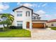 Beautiful two-story home featuring a tile roof, wood garage door, manicured lawn, and lush landscaping at 10824 Royal Cypress Way, Orlando, FL 32836