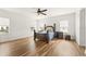 Light filled primary bedroom with hardwood flooring, ceiling fan and three windows at 10824 Royal Cypress Way, Orlando, FL 32836