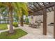 Outdoor kitchen with stainless steel grill, dining area, travertine pavers, and lush landscaping at 10824 Royal Cypress Way, Orlando, FL 32836