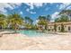 Resort style pool with plenty of seating and beautiful landscaping surrounded by palm trees in a tropical community at 10824 Royal Cypress Way, Orlando, FL 32836