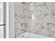 Close up on the shower and tub area with a marble-look tile surround and shower head at 1932 Lake Atriums Cir # 69, Orlando, FL 32839