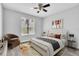 This staged bedroom features wood-look floors, a ceiling fan, and a bright window at 1932 Lake Atriums Cir # 69, Orlando, FL 32839