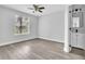 This bedroom features wood-look flooring, a ceiling fan, a bright window, and a bathroom entryway at 1932 Lake Atriums Cir # 69, Orlando, FL 32839