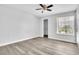 This bedroom features wood-look flooring, a ceiling fan, a walk-in closet, and a bright window at 1932 Lake Atriums Cir # 69, Orlando, FL 32839