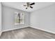 This bedroom features wood-look flooring, a ceiling fan, and a bright window at 1932 Lake Atriums Cir # 69, Orlando, FL 32839