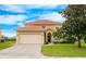 Two-story house with a beige exterior, a large garage, and a well-manicured lawn at 412 Vista Dr, Davenport, FL 33897