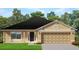 One-story house with a tan exterior, dark roof, and two-car garage at 4472 Sagefield Dr, St Cloud, FL 34773
