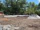 New home construction featuring a concrete slab foundation surrounded by a lush, wooded landscape at 25122 Ensley Rd, Sorrento, FL 32776