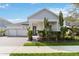 Two-story home with gray siding, paver driveway, and lush landscaping at 3032 Ella Way, St Cloud, FL 34771