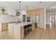 Modern kitchen with light wood cabinets, quartz countertops, and stainless steel appliances at 3032 Ella Way, St Cloud, FL 34771