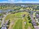 Aerial view showcasing a golf course surrounded by houses, lakes, and vast natural landscapes at 5024 St Andrews Arc, Leesburg, FL 34748