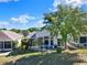Backyard view features a patio with chairs, barbecue grill, and well-manicured lawn and landscaping at 5024 St Andrews Arc, Leesburg, FL 34748