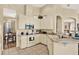 Well-lit kitchen with tile flooring, white appliances, and a breakfast bar overlooking an adjacent dining area at 5024 St Andrews Arc, Leesburg, FL 34748