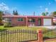 Charming brick home with a red metal roof, arched entryway, and decorative black fence at 930 Lewis Dr, Daytona Beach, FL 32117