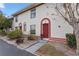 Inviting townhome featuring a charming red door and arched entryway, complemented by well-maintained landscaping at 1606 Sandy Point Sq # 53, Orlando, FL 32807