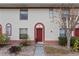 Close up view of a townhome entrance, featuring a red door, arched entryway, and manicured landscaping at 1606 Sandy Point Sq # 53, Orlando, FL 32807