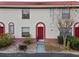 Inviting condo exterior featuring a red door and well-maintained landscaping at 1606 Sandy Point Sq # 53, Orlando, FL 32807