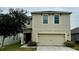 Two-story house with beige siding, two-car garage, and landscaping at 3033 Timber Hawk Cir, Ocoee, FL 34761