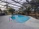 Backyard pool with a screened enclosure, a concrete pool deck and landscaping at 770 Mink Ct, Poinciana, FL 34759