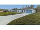 Well-maintained property featuring a long driveway, manicured lawn, and a blue garage door at 15136 Sw 61St Court Rd, Ocala, FL 34473