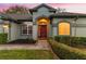 Charming home exterior with a red front door and lush, landscaped yard at 15336 Firelight Dr, Winter Garden, FL 34787